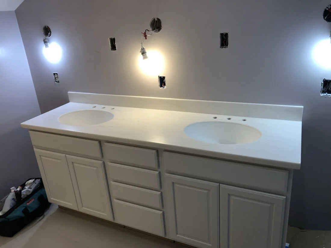 a bathroom with white counter tops and lights